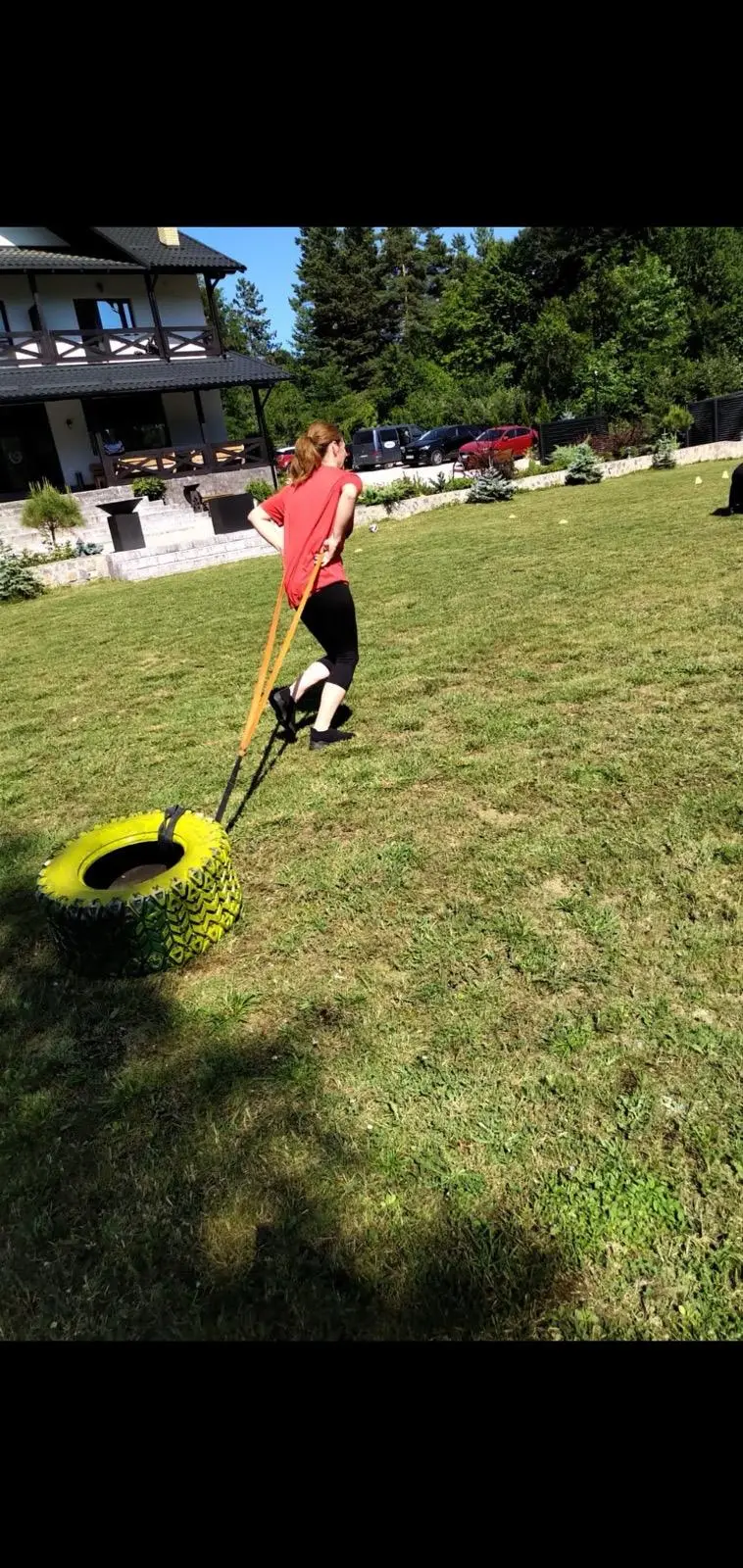 Participantă la un exercițiu de antrenament funcțional cu anvelopă, pe iarbă